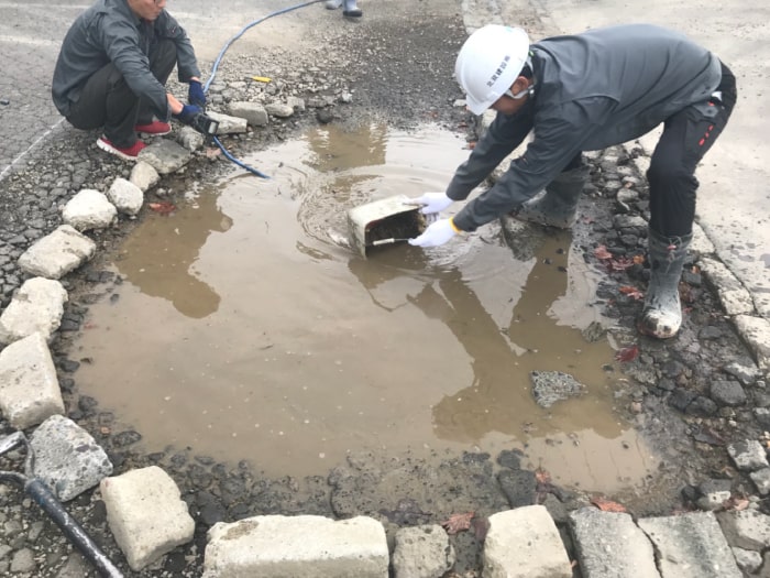 駐車場の水溜まりアスファルト補修工事。泥水を除去する様子