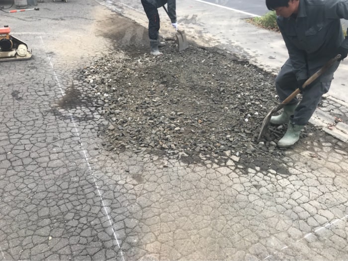 駐車場の水溜まりアスファルト補修工事。路盤材を補充している様子