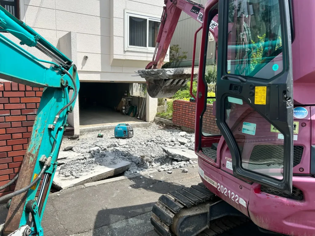 札幌市東区の一般住宅（玄関車庫前）土間コンクリートを重機で解体する様子